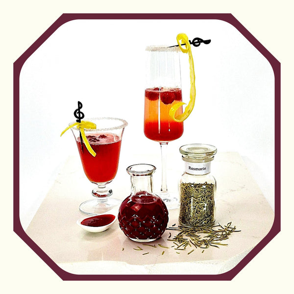 Rosmarin im Glas neben einem Glas Rosmarin-Himbeer-Spritz mit Sekt, einem Glas Rosmarin-Himbeer-Spritz mit Wasser, einer kleinen Flasche Rosmarin-Sirup und einem Löffel mit Rosmarin-Sirup gefüllt